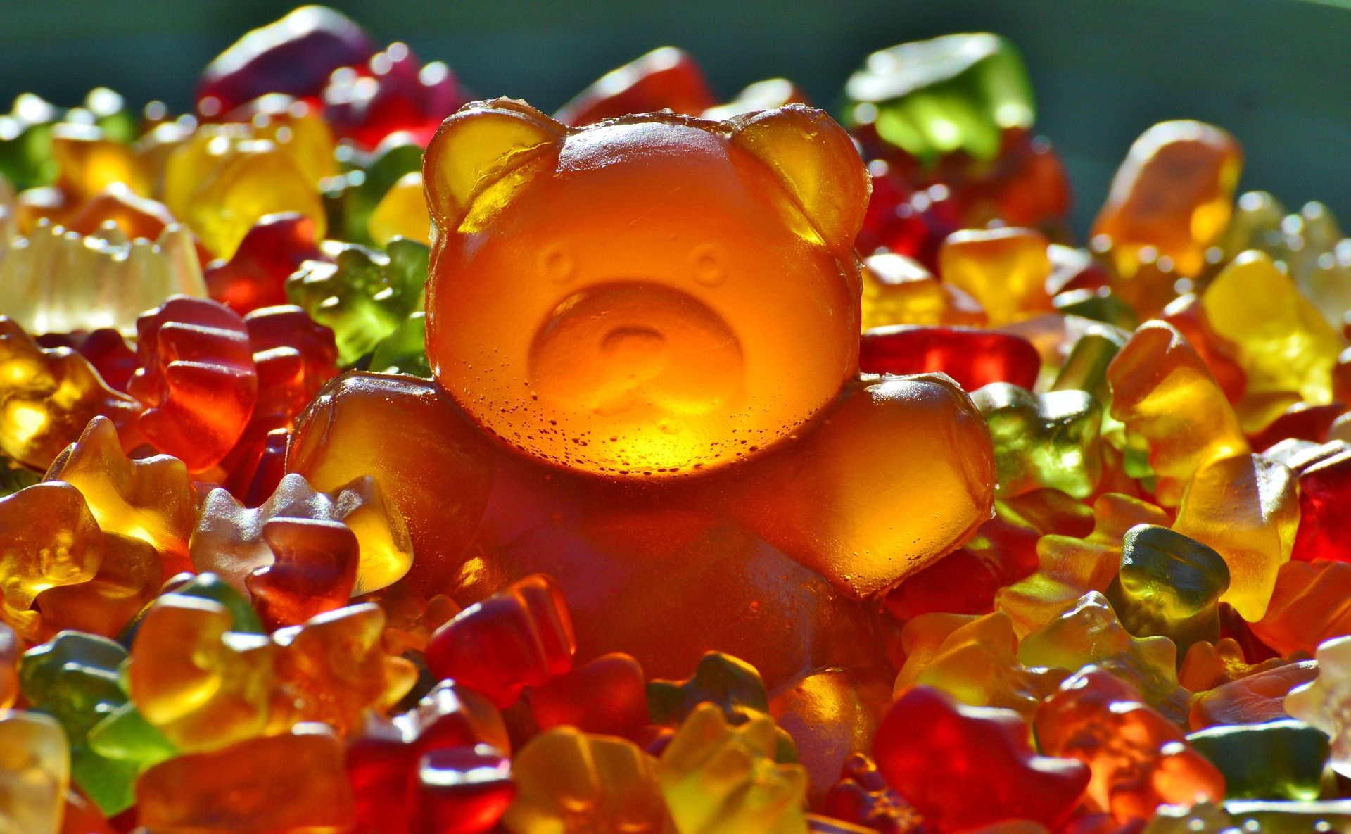 viele Gummibären in verschiedenen Farben mit einem großen Gummibären in der Mitte